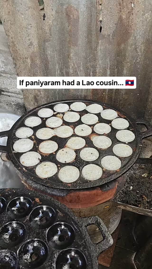 This is Khao nom krok, one of the most popular street snacks in Laos 🇱🇦 in Southeast Asia. The moment I saw it, I couldn't help but think of paniyaram.

Both are cooked in the same kind of mould, both have that perfectly round shape with a crisp outside and soft centre, and both are best eaten hot off the pan.

But that's where the similarities end. Paniyaram is usually made with fermented rice🌾 and lentil batter and is mostly savoury. Khao nom krok is made with rice flour and coconut milk🥥, so it's creamy, slightly sweet, and almost custard-like inside.

Travel has a funny way of making the unfamiliar feel familiar.